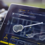 A modern digital tablet showing a glossary of Lacrosse terms, featuring lacrosse sticks, set against a sports field, highlighting data visualization.