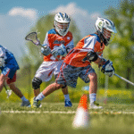 Young athletes engaged in fun youth Lacrosse drills around cones on the field.
